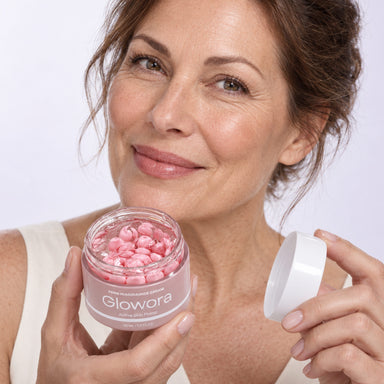 Glimlachende vrouw houdt een geopende pot PDRN Niacinamide Crème met roze capsules vast